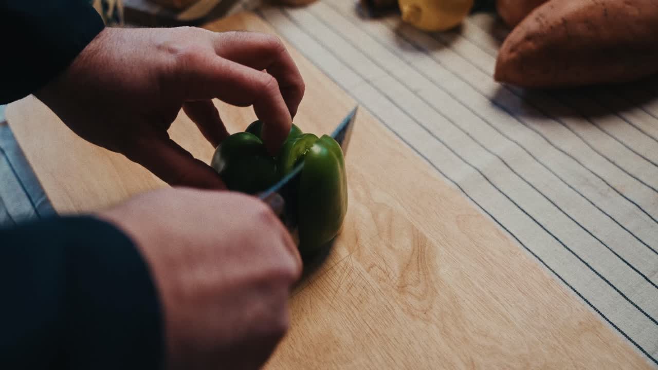 평범한 주방에서 나무로 만든 절단판에 초록색 고추를 잘라내는 사람