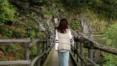 woman walking on a wooden bridge in a forest