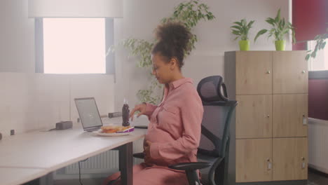 Schwangere-Frau-Isst-Pommes-Am-Schreibtisch-Im-Büro
