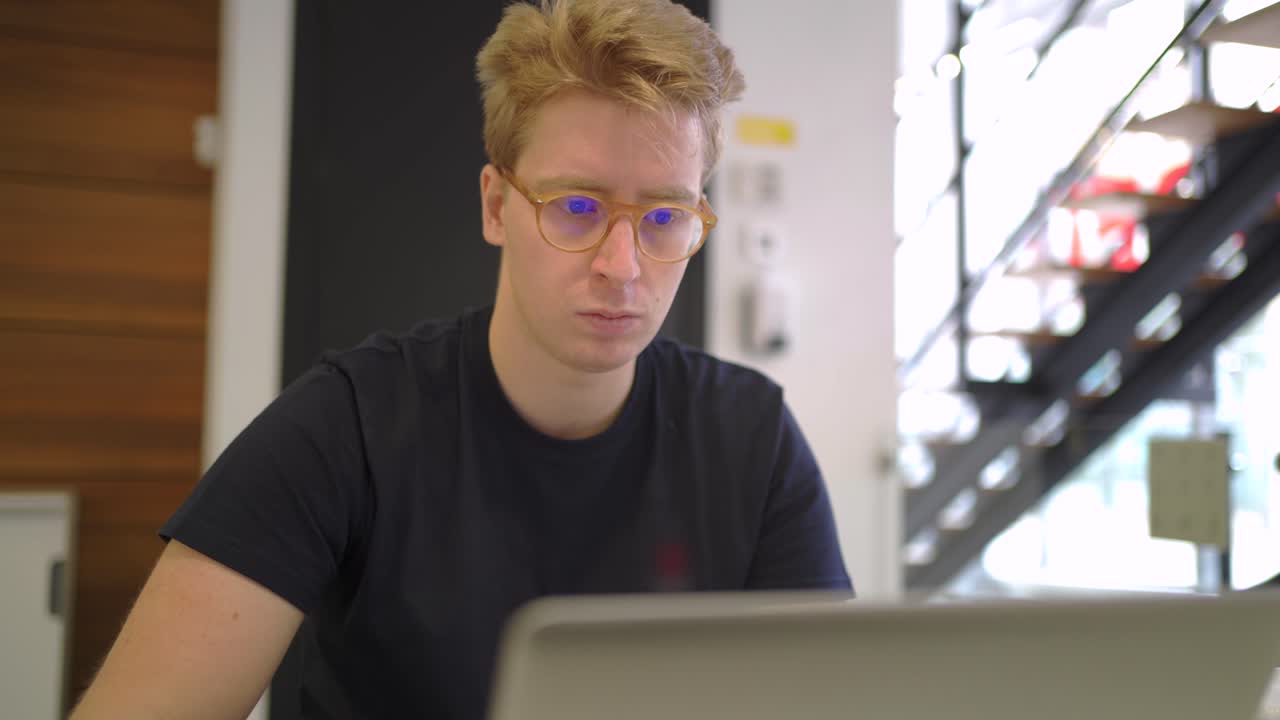 uomo con gli occhiali che lavora su un laptop in ufficio