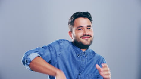 un joven bailando contra un fondo gris