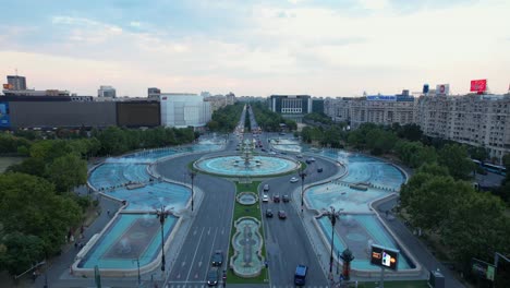 Bukarests-Unirii-Platz-In-Der-Abenddämmerung:-Luftaufnahme-Der-Berühmten-Blauen-Wasserfontänen-Und-Des-Geschäftigen-Verkehrs