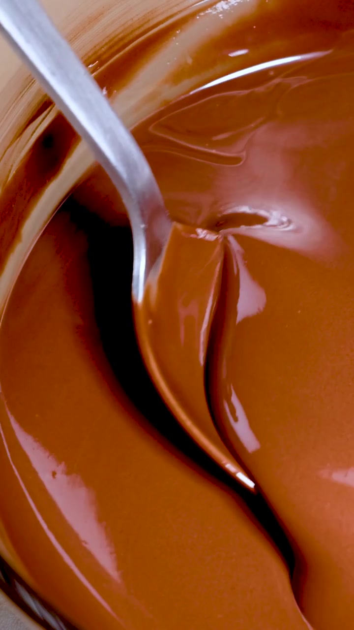 Cucchiaio che mescola cioccolato fuso e vellutato in una ciotola di vetro