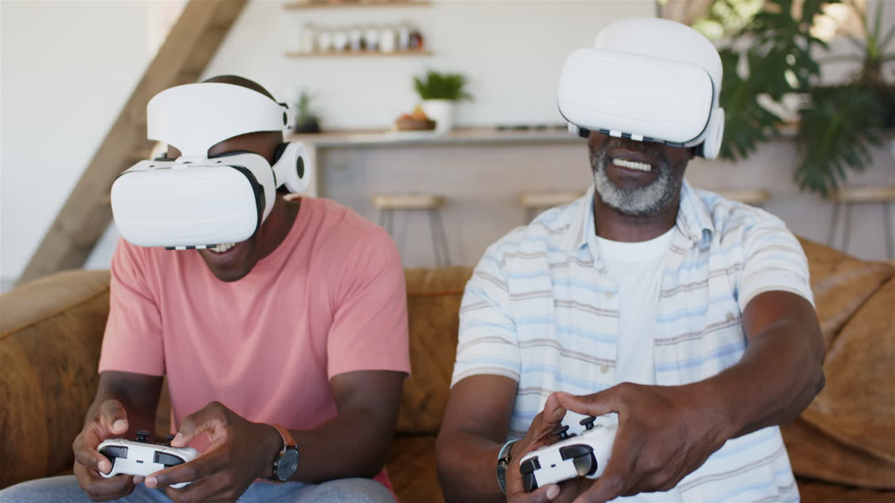 Giocando ai videogiochi con visori VR, padre e figlio adulto si godono un'esperienza di realtà virtuale.