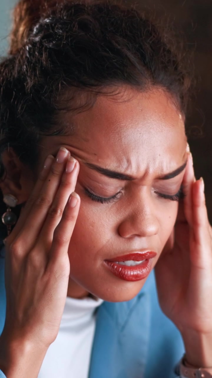Stressed Young Woman Rubbing Her Temples in Office
