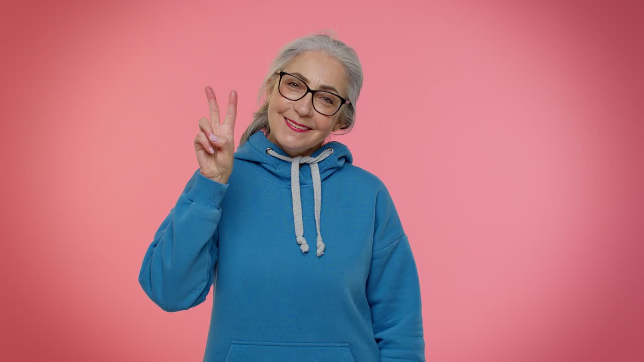 abuela madura mostrando el signo de la victoria, esperando el éxito y la victoria, haciendo un gesto de paz, sonriendo