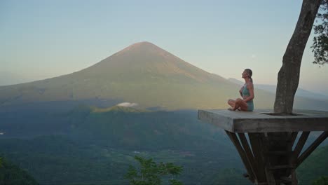 woman on platform breathing technique for stress relief with mount agung in background