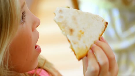 chica comiendo pizza en la cocina 4k