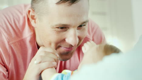 portrait of a young attractive father happily looking at sveogo child close-up baby holds his finger