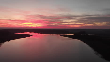 Panning-drone-footage-of-a-fantastic-sunset-with-a-lake-and-forest-underneath