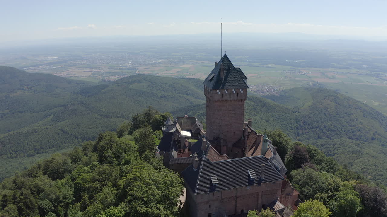 Circulating aerial shot showing details of a renovated medieval castle in the Alsace region of France. Background shows vineyard landscape