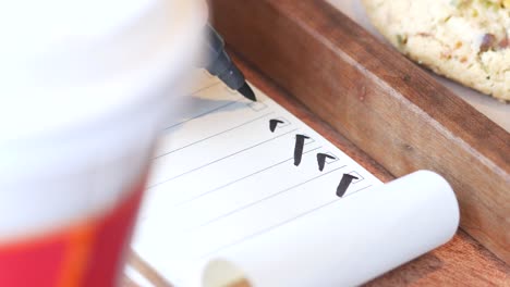 close-up of a checklist being filled out on a wooden tray