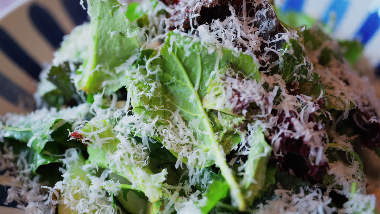 Close up of a salad with leafy green and grated parmesan on top