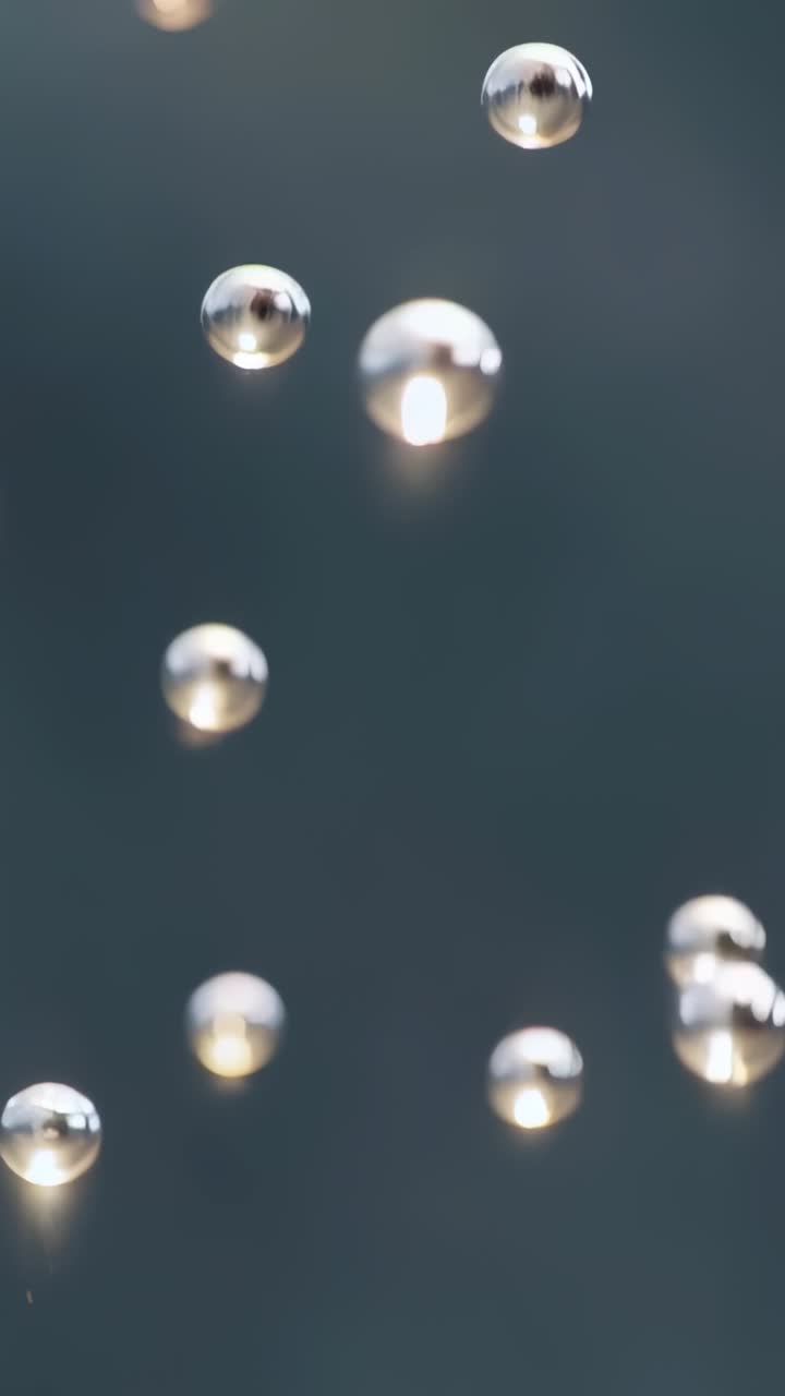 Video verticale: goccioline riflettenti che formano striature in macro studio, attivate dall'otturatore