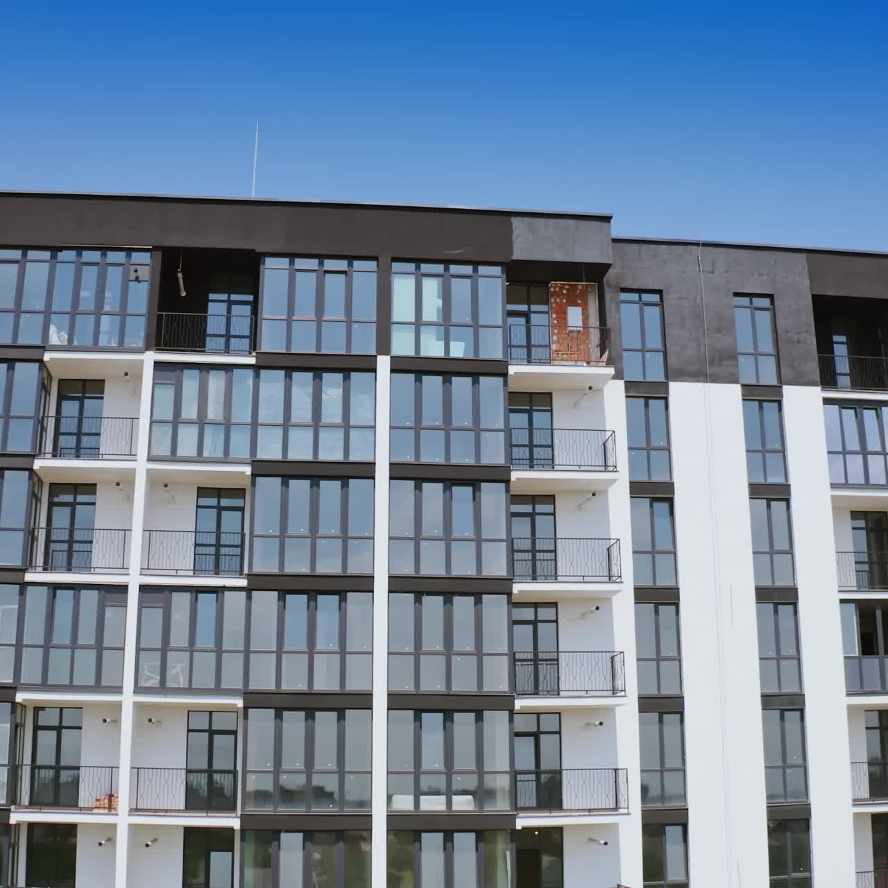 Front view of a beautiful multi-storey building. Modern design of high-raised apartment building with many glass windows and balconies. Aerial view