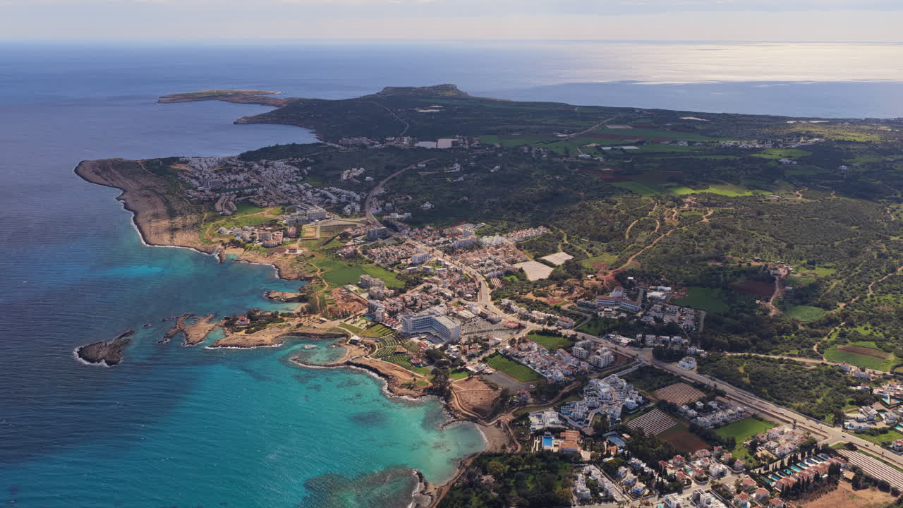 Veduta aerea con drone della penisola di Cape Greco, Cipro, caratterizzata da una costa frastagliata, piccole baie e vegetazione naturale circondata dalle acque blu intenso del Mediterraneo.