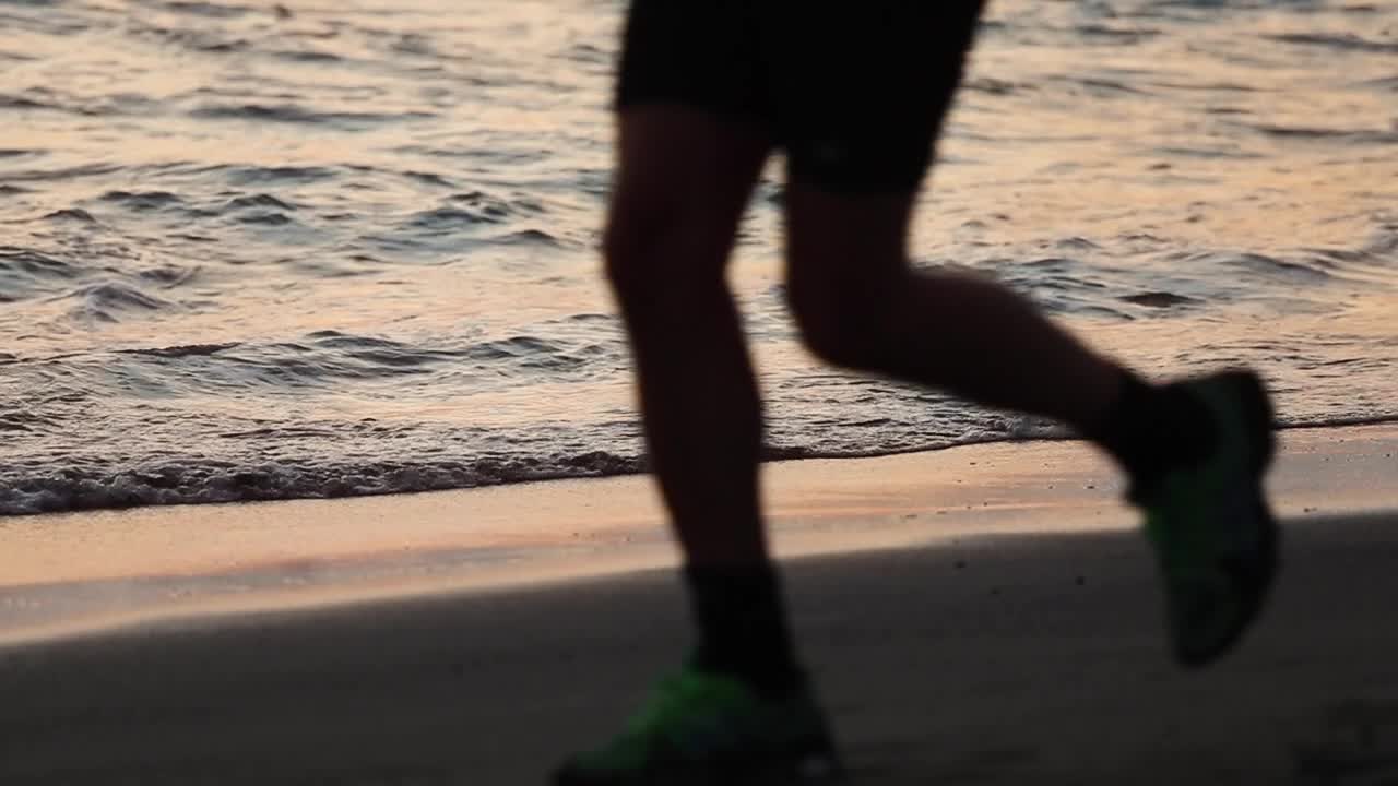 trotar en la playa cerca de las olas durante la puesta de sol, hermoso - cámara lenta