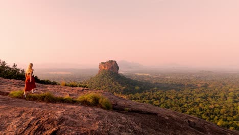 a young woman runs across the summit of pidurangala rock to catch the magical sunrise over sigiriya rock.