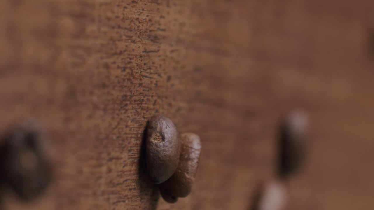 los granos de café tostados caen sobre una mesa de madera - toma del producto