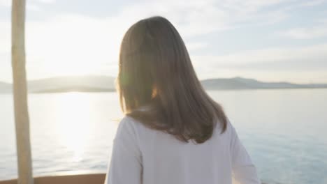 medium closeup shot of a girl standing by the sea, gazing upon the sun while it sets