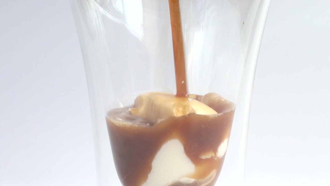 Preparazione di caffè freddo con gelato, panna montata e topping al cioccolato
