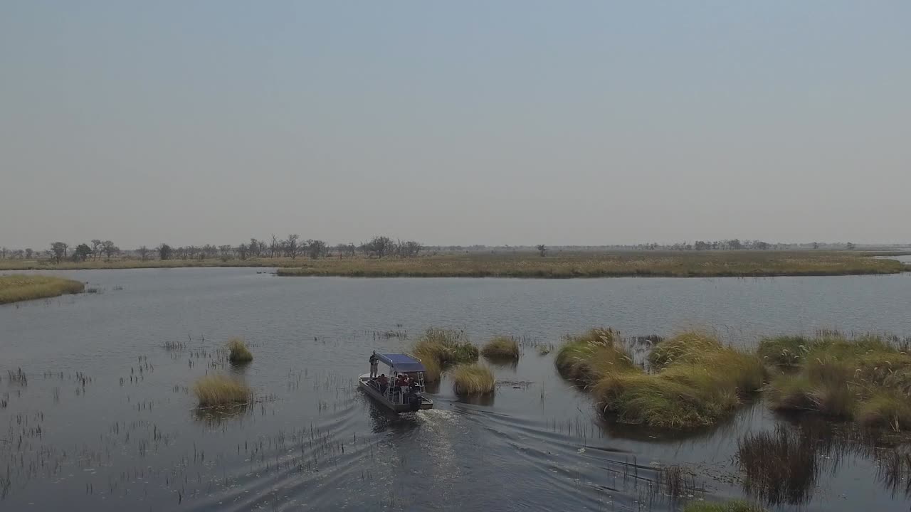 Aerial shot of a boat with tourists sailing down the river at Okavango Delta in Botswana