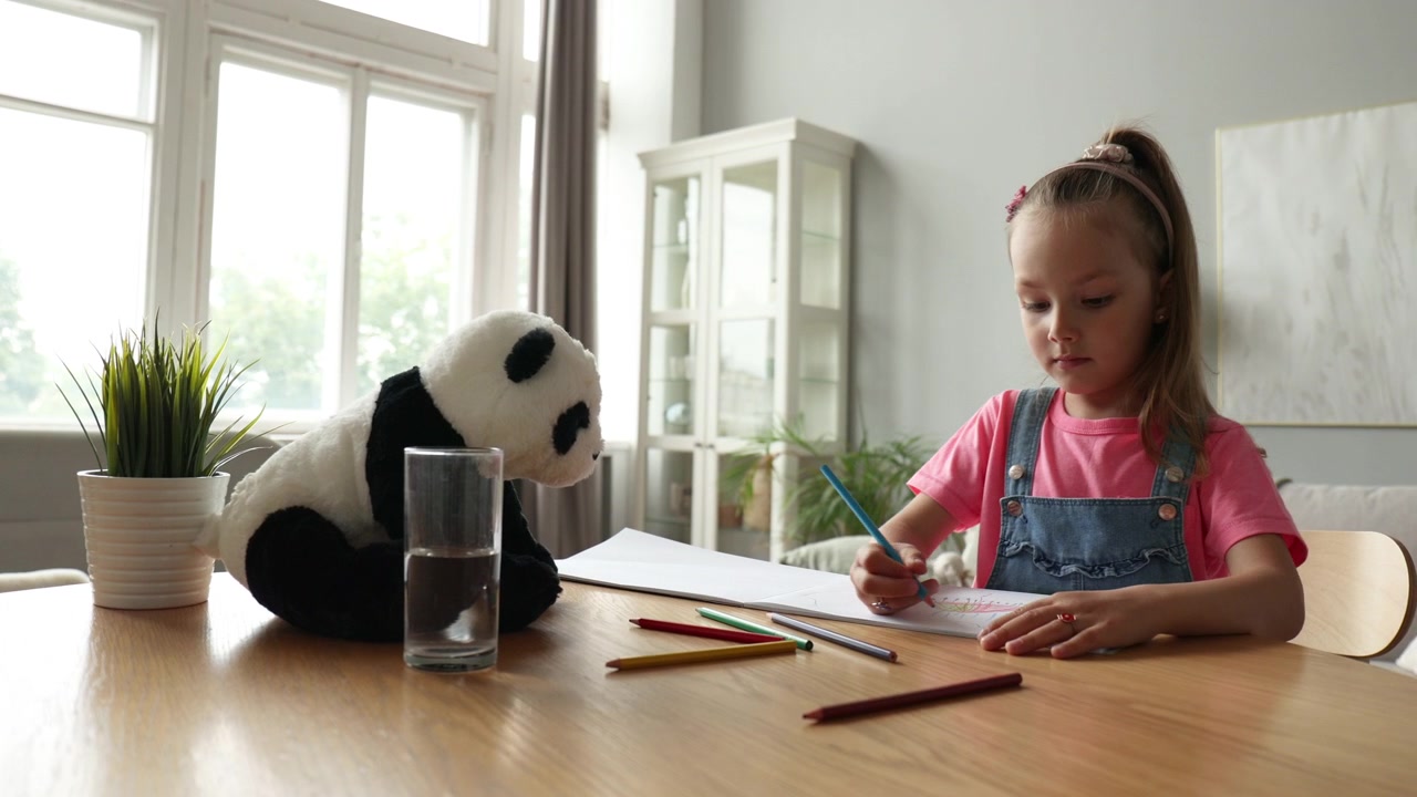 Little Girl Drawing with Colored Pencils at Home Table
