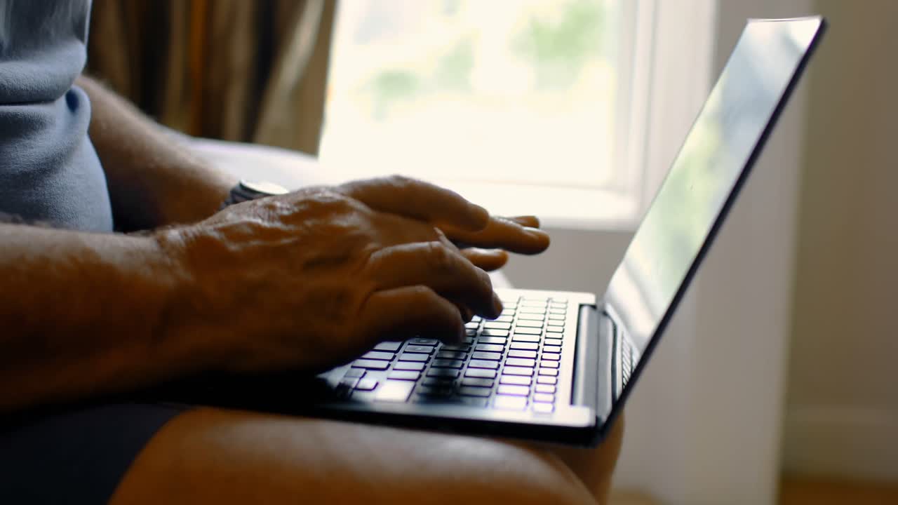 Mid section of senior man using laptop in a comfortable home 4k