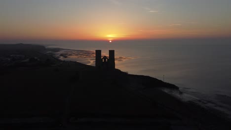 silhouette of reculver towers against orange sunset skies