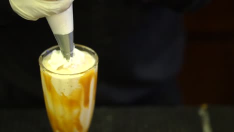 fresh cream being applied to milkshake with caramel