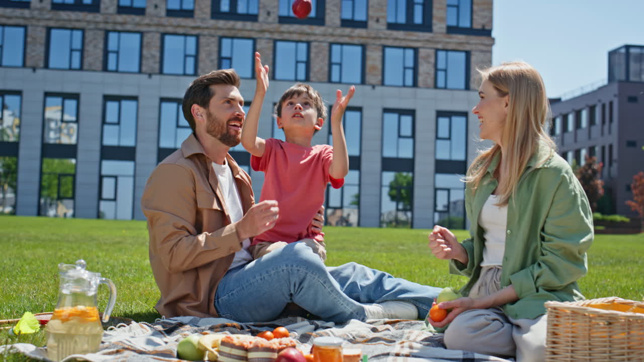 Young family resting summer weekend. Happy parents lunching with child on picnic