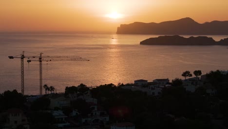 Aerial---deep-yellow-sunset-sky-over-Mediterranean-bay-coastline,-Mallorca