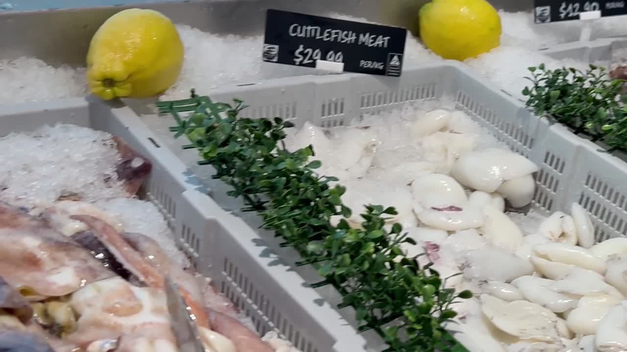 Close-up view of fresh cuttlefish and octopus on ice, garnished with lemons and greenery.