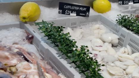 close-up view of fresh cuttlefish and octopus on ice, garnished with lemons and greenery.