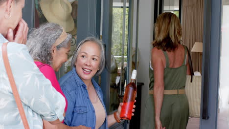 senior biracial woman greets friends at her home's entrance