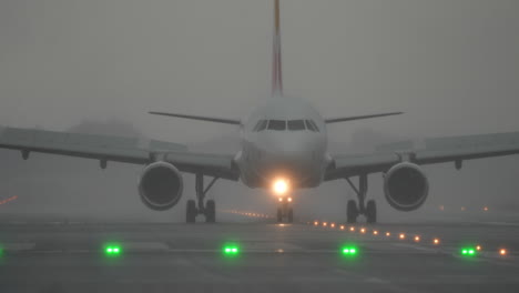 airplane approaches runway in foggy conditions during rain