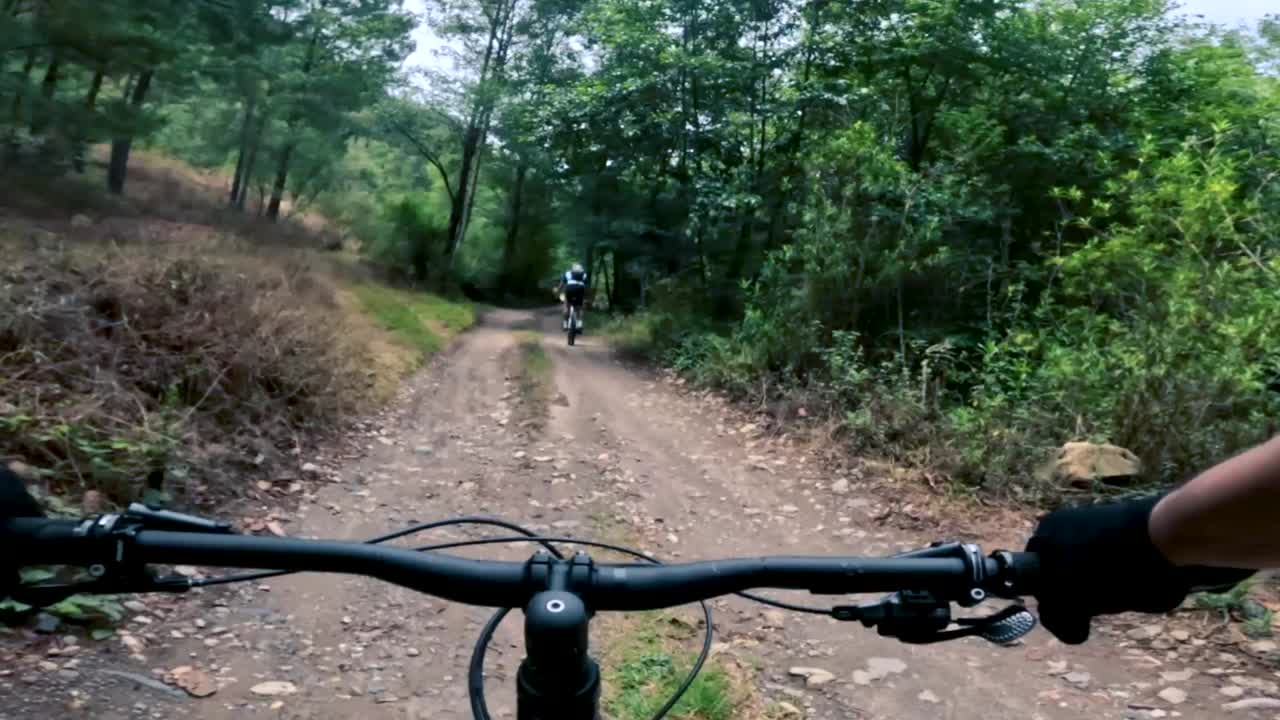 dos ciclistas andan en bicicleta por una carretera dentro de un bosque, una colina y un pueblo en guatemala, américa del norte