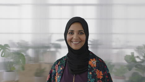 portrait-of-senior-muslim-business-woman-smiling-looking-happy-at-camera-wearing-traditional-headscarf-mature-experienced-female-in-office-workspace