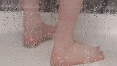 male feet in a shower cubicle as the person takes a shower, locked off