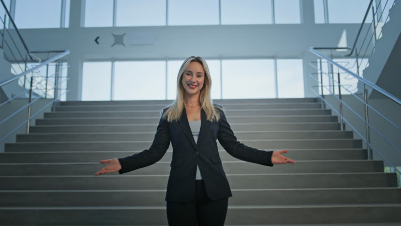 Businesswoman standing outstretched arms on staircase office. Smiling woman