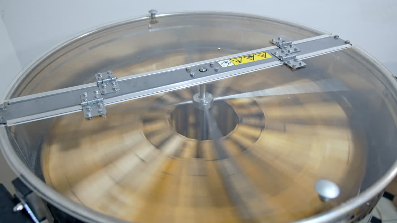 Spinning of frames with honey in a honey extractor. Process of pumping natural honey in modern centrifuge machine. Getting honey from honeycombs in special device. Close-up.