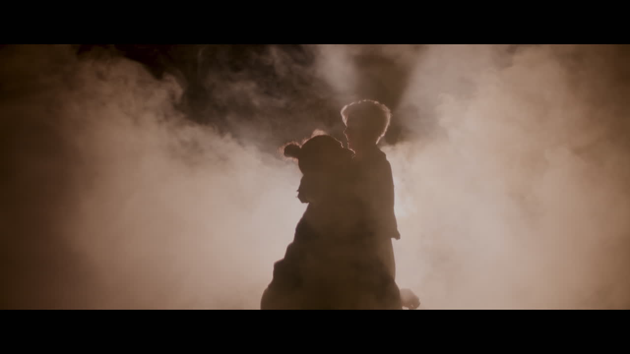 Silhouette of a Parent and Child in Smoky Darkness