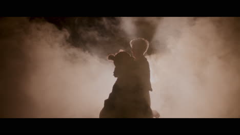 silhouette of a parent and child in smoky darkness