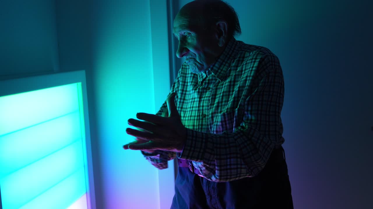 Uomo anziano in piedi al chiuso vicino a una luce colorata