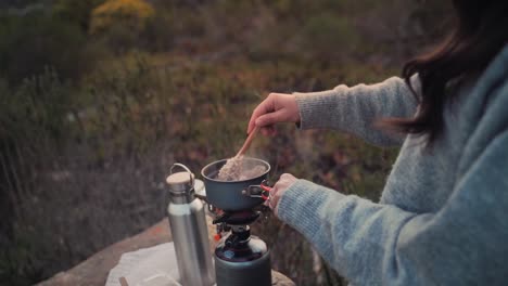 Slow-motion-footage-of-a-heavily-dressed-woman-cooking-while-camping-out-in-the-wild