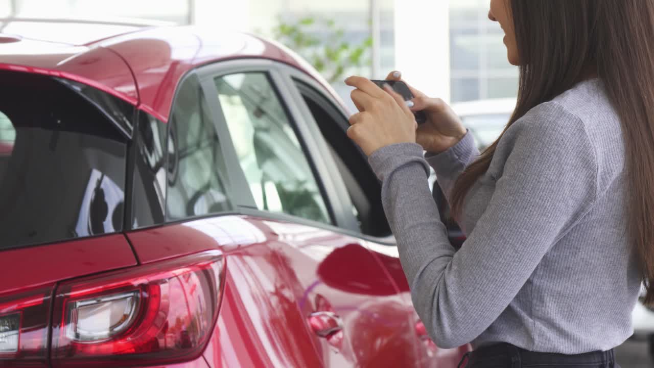 fotografía recortada de una mujer tomando fotos de su nuevo coche