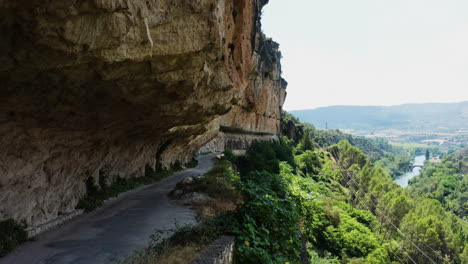 Dolly-in-aerial-shot-of-Mirador-el-Puente-Romano-road-and-forested-hill