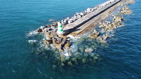 Lighthouse-located-in-a-port-at-Portugal,-waves,-ships-and-rocks