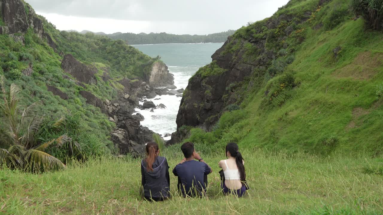 Three People Enjoying a Scenic View of a Coastal Valley