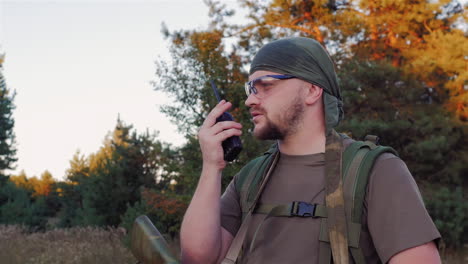 man in camouflage with guns speaking on the radio